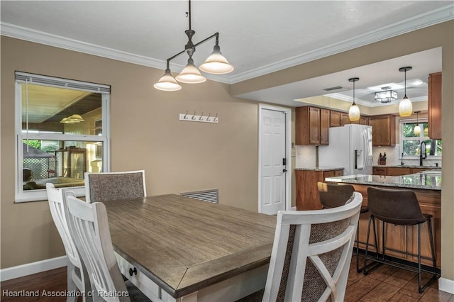 dining space with dark hardwood / wood-style flooring, ornamental molding, and sink