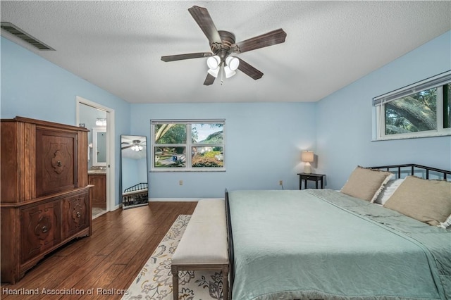 bedroom with a textured ceiling, ensuite bathroom, ceiling fan, and dark hardwood / wood-style floors