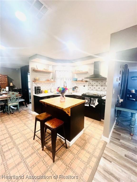300 Whatley Blvd, Sebring, FL 33870 - kitchen with wall chimney exhaust hood, open shelves, wooden counters, and tasteful backsplash