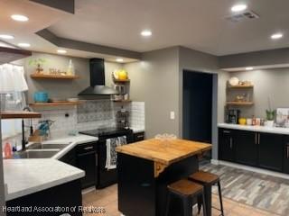 300 Whatley Blvd, Sebring, FL 33870 - kitchen featuring open shelves, wall chimney exhaust hood, black range with electric cooktop, dark cabinets, and decorative backsplash