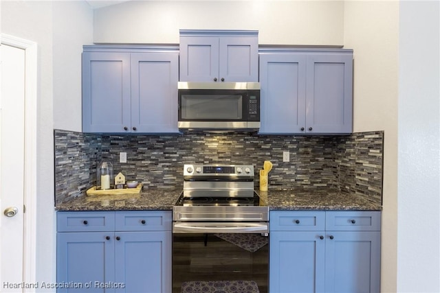 kitchen featuring backsplash, blue cabinetry, stainless steel appliances, and dark stone counters