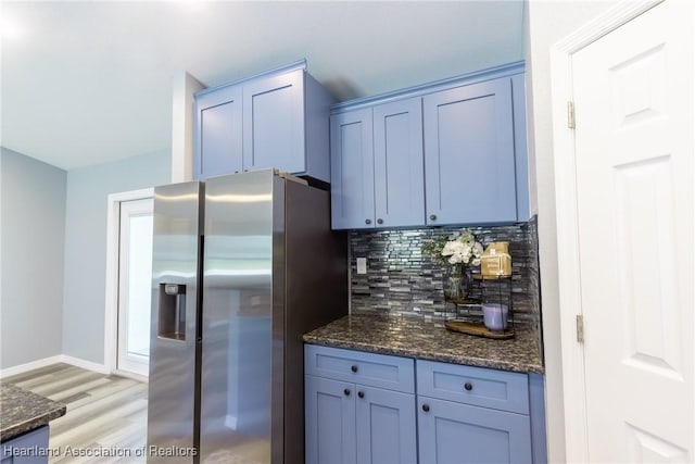 kitchen with stainless steel fridge with ice dispenser, blue cabinets, backsplash, dark stone counters, and light hardwood / wood-style floors