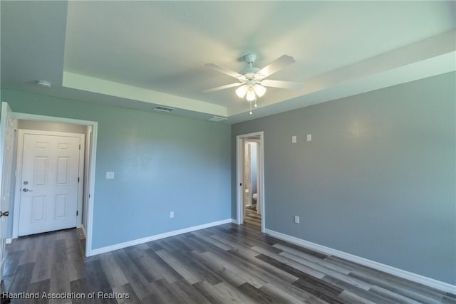 spare room with a raised ceiling, ceiling fan, and dark hardwood / wood-style floors