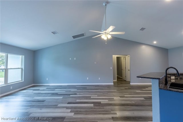 unfurnished living room with lofted ceiling, ceiling fan, dark wood-type flooring, and sink