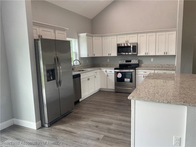3900 Santiago St, Sebring, FL 33872 - kitchen featuring stainless steel appliances, high vaulted ceiling, white cabinets, light stone countertops, and wood finished floors