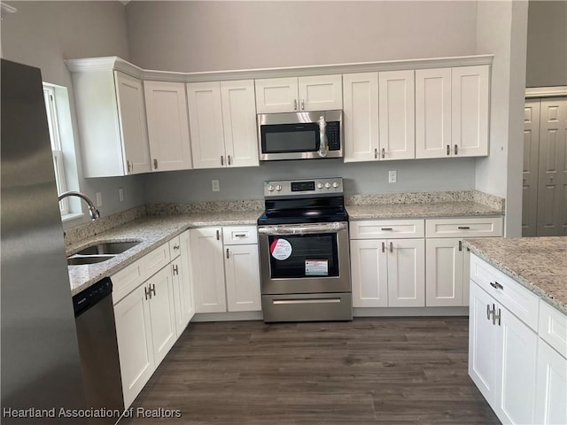3900 Santiago St, Sebring, FL 33872 - kitchen with appliances with stainless steel finishes, white cabinetry, dark wood-style flooring, and light stone countertops