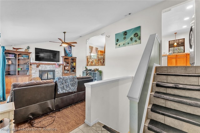 5324 Lafayette Ave, Sebring, FL 33875 - living area featuring ceiling fan, a stone fireplace, vaulted ceiling, stairs, and light tile patterned flooring