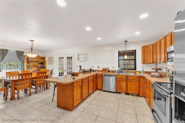 5324 Lafayette Ave, Sebring, FL 33875 - kitchen with brown cabinets, a sink, light tile patterned floors, a peninsula, and stainless steel appliances
