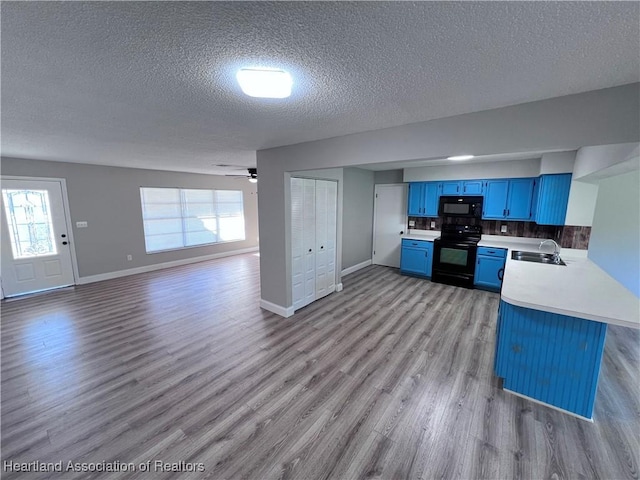 kitchen featuring light hardwood / wood-style flooring, blue cabinetry, black appliances, ceiling fan, and kitchen peninsula