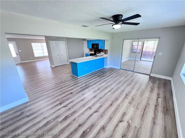 interior space with ceiling fan, light hardwood / wood-style flooring, and a textured ceiling