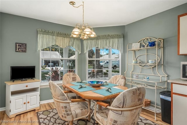 dining area featuring light wood-type flooring and an inviting chandelier