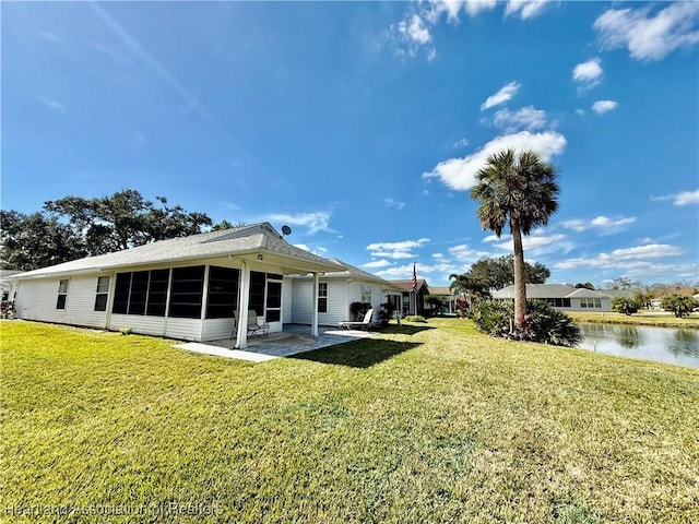 rear view of property featuring a water view, a yard, and a patio area