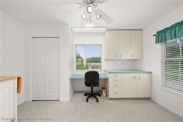 carpeted office with built in desk and ceiling fan