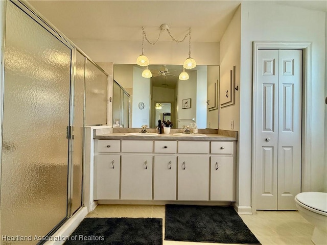 bathroom featuring a shower with door, vanity, tile patterned floors, and toilet