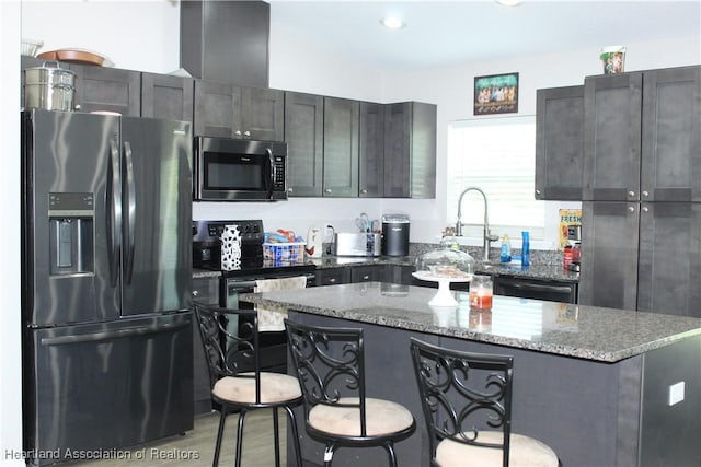 5195 Greenfields Run, Zolfo Springs, FL 33890 - kitchen featuring appliances with stainless steel finishes, stone counters, a kitchen breakfast bar, a kitchen island, and light wood-style floors