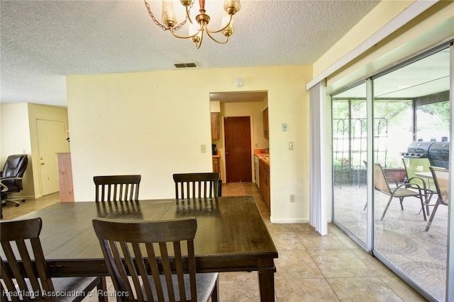 dining space with a chandelier, a textured ceiling, and light tile patterned flooring