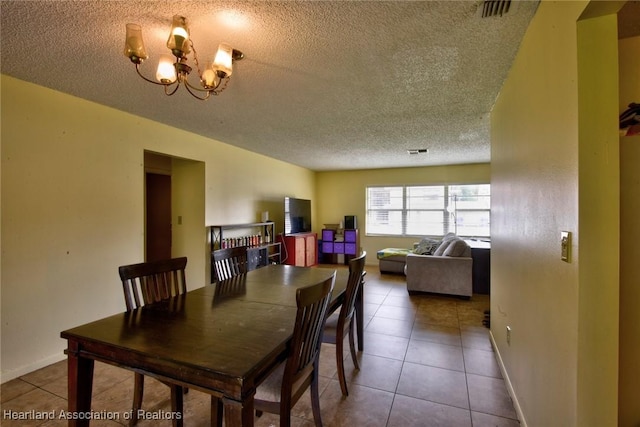 dining area featuring tile patterned flooring, a notable chandelier, and a textured ceiling