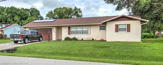 single story home featuring a garage, a front yard, and solar panels