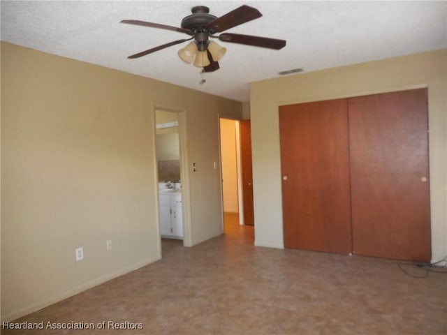 unfurnished bedroom with ceiling fan, a closet, and ensuite bathroom