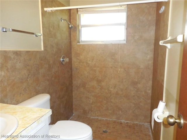 bathroom featuring vanity, toilet, and tiled shower