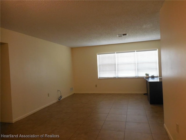 spare room with tile patterned floors and a textured ceiling