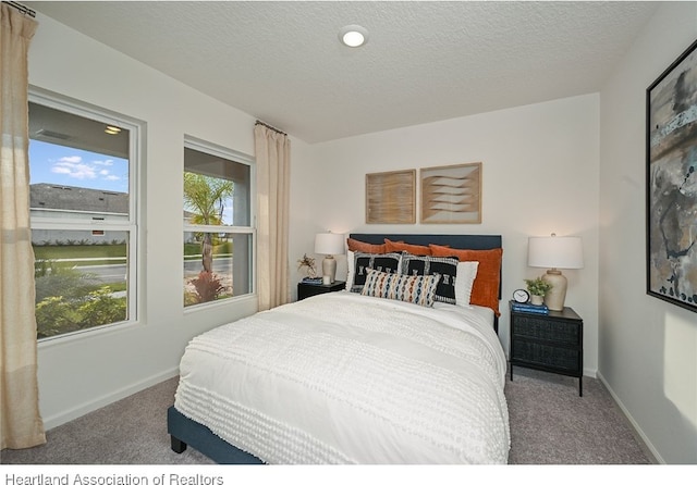 carpeted bedroom with a textured ceiling and multiple windows