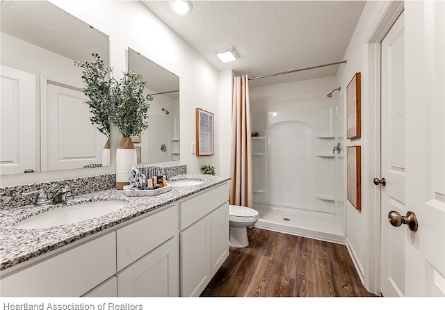 bathroom with vanity, hardwood / wood-style flooring, toilet, a textured ceiling, and walk in shower