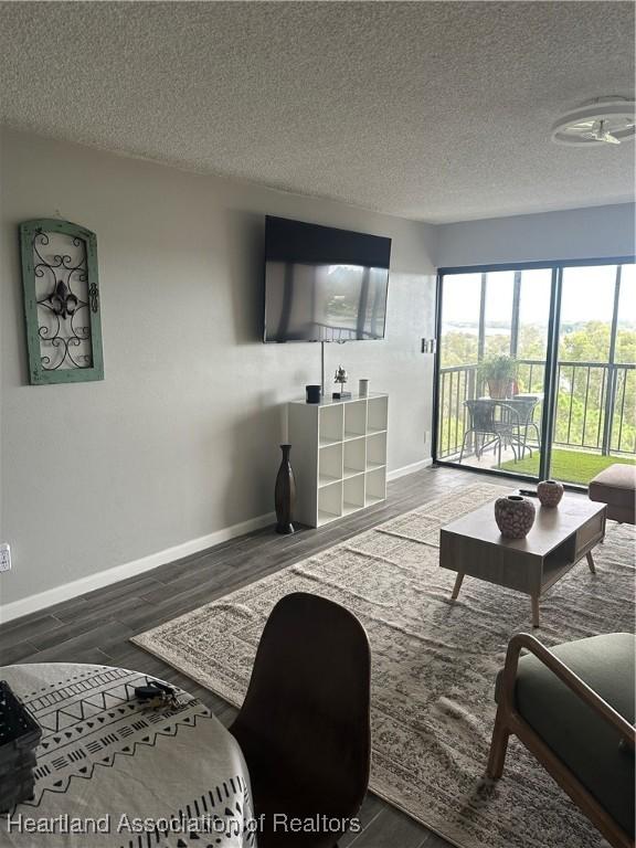 living room featuring dark wood-type flooring and a textured ceiling