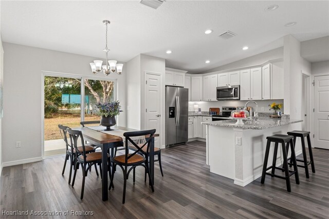 9131 Canter Path, Sebring, FL 33875 - kitchen with stainless steel appliances, a peninsula, a chandelier, dark wood finished floors, and white cabinetry
