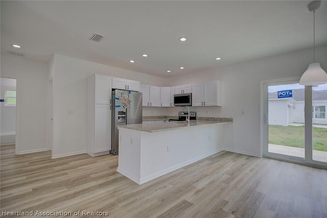 kitchen featuring kitchen peninsula, decorative light fixtures, light stone counters, white cabinetry, and stainless steel appliances