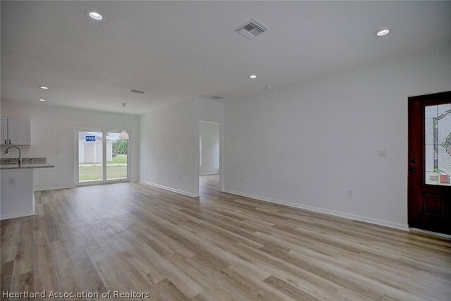 unfurnished living room with light hardwood / wood-style floors and sink