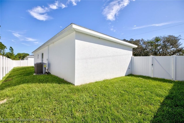 view of side of property featuring a yard and central AC