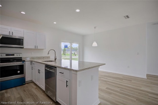 kitchen featuring kitchen peninsula, appliances with stainless steel finishes, decorative light fixtures, and white cabinetry