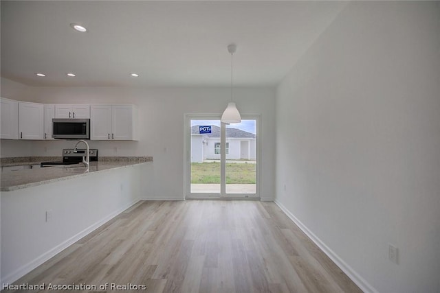 kitchen featuring light stone countertops, appliances with stainless steel finishes, decorative light fixtures, white cabinets, and light hardwood / wood-style floors