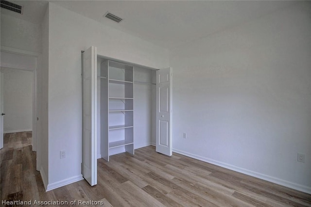 unfurnished bedroom with light hardwood / wood-style flooring and a closet