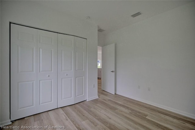 unfurnished bedroom featuring light hardwood / wood-style flooring and a closet