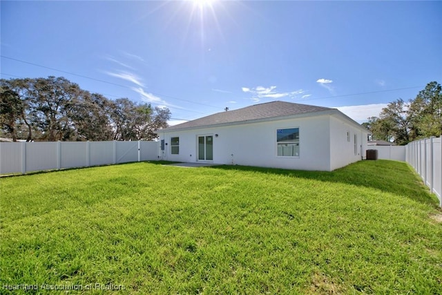 back of property with central AC and a lawn