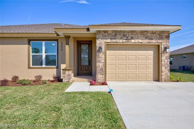 view of front of house featuring central AC, a garage, and a front yard