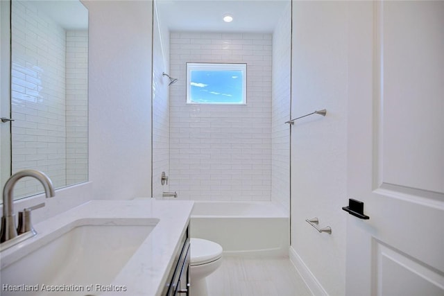 full bathroom featuring vanity, tiled shower / bath, and toilet