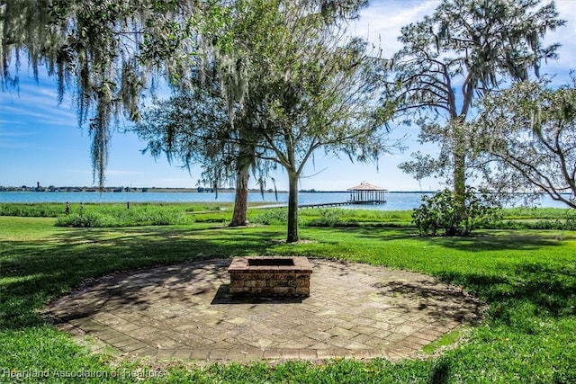 view of community with a lawn, a gazebo, a water view, an outdoor fire pit, and a patio area