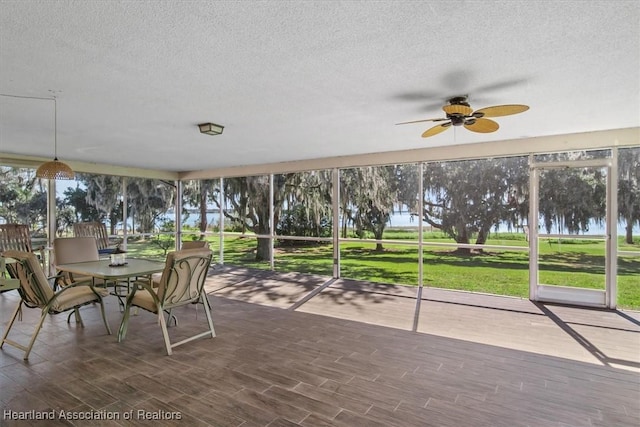 unfurnished sunroom featuring a water view and ceiling fan