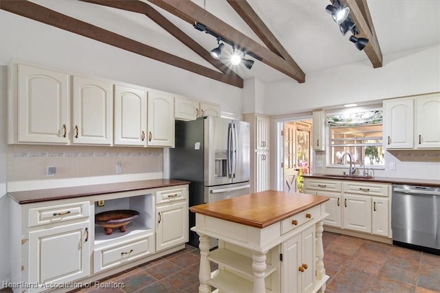kitchen with vaulted ceiling with beams, decorative backsplash, white cabinets, and appliances with stainless steel finishes