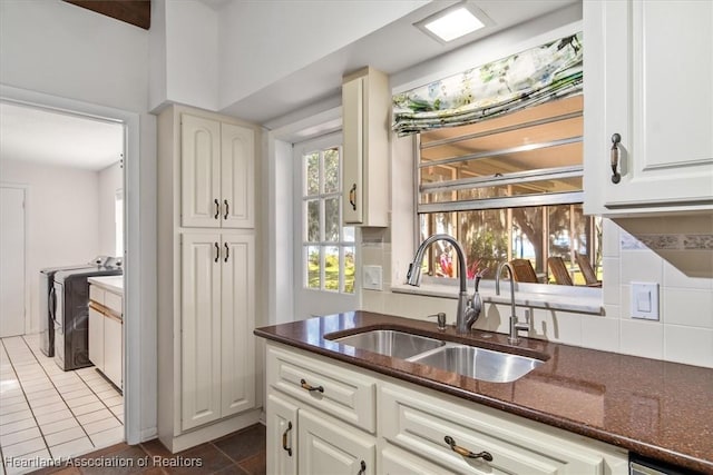 kitchen with sink, white cabinetry, dark stone countertops, tasteful backsplash, and separate washer and dryer