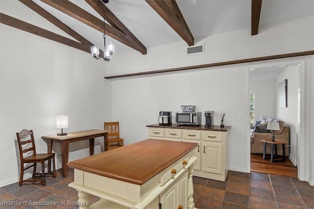 kitchen with cream cabinets, decorative light fixtures, vaulted ceiling with beams, and a chandelier