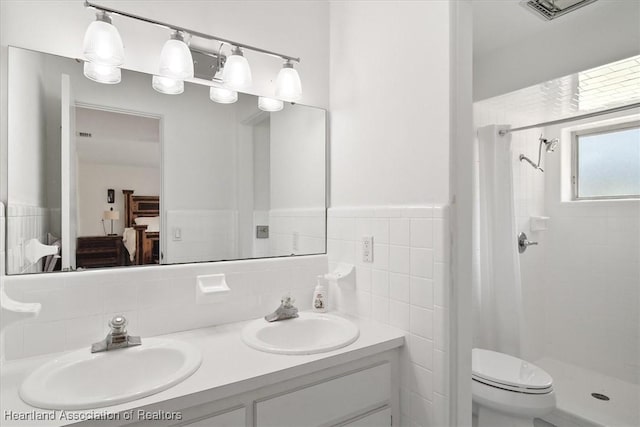 bathroom with vanity, a tile shower, tile walls, and toilet