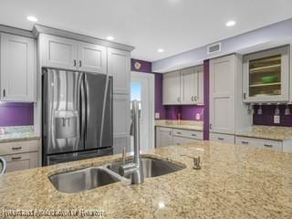 2131 Lakeview Dr Unit 1008, Sebring, FL 33870 - kitchen featuring stainless steel fridge, light stone counters, recessed lighting, and glass insert cabinets