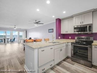 2131 Lakeview Dr Unit 1008, Sebring, FL 33870 - kitchen featuring stainless steel appliances, open floor plan, a peninsula, light wood-style flooring, and a ceiling fan