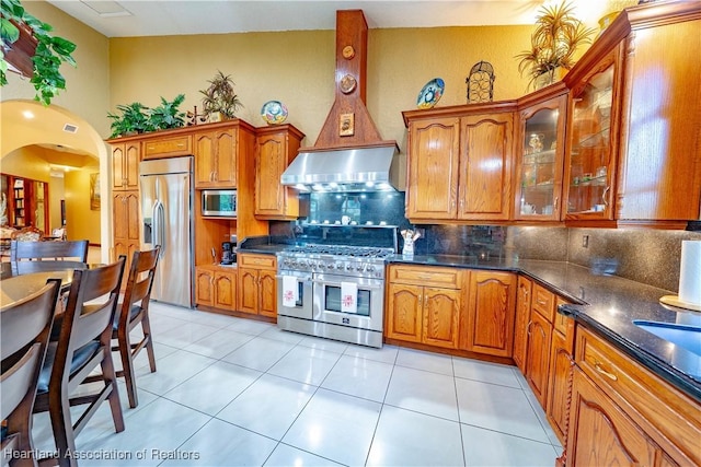 14630 Luray Rd, Southwest Ranches, FL 33330 - kitchen with built in appliances, range hood, backsplash, arched walkways, and brown cabinetry