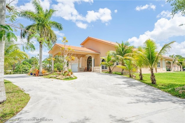 14630 Luray Rd, Southwest Ranches, FL 33330 - mediterranean / spanish-style house featuring curved driveway, a garage, stucco siding, a front lawn, and a tile roof