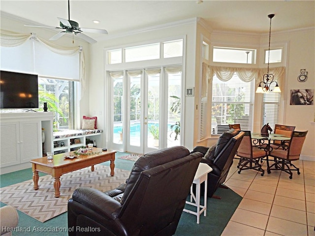 tiled living room with a healthy amount of sunlight, ceiling fan with notable chandelier, and ornamental molding